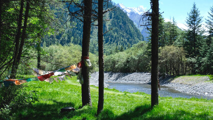 Fototapeta premium The river, mountain range and greenery forest with prayer flag blowing in the wind, Chengdu China