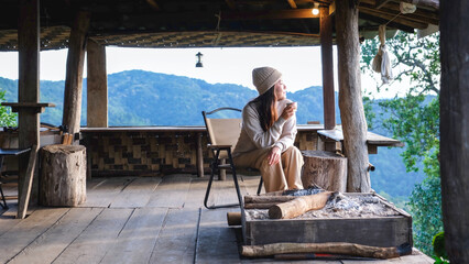 Fototapeta premium A woman sitting on wooden terrace and looking at nature views