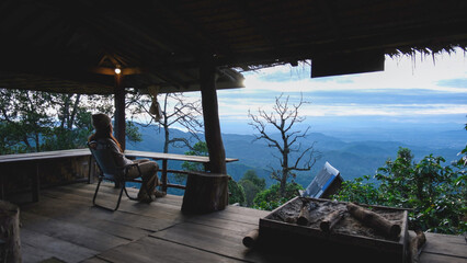 Fototapeta premium A woman sitting on wooden terrace and looking at nature views