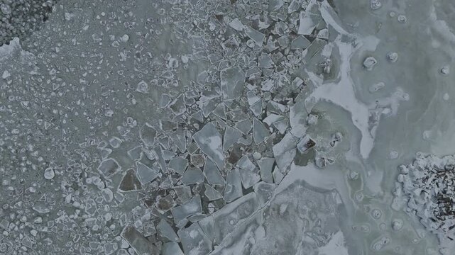 Top down aerial drone view of broken sea ice floes and frozen water texture