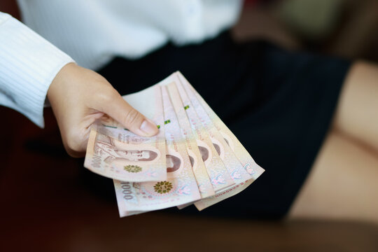 Working woman or Office lady holding Thai baht banknotes, representing finance, income, salary, savings, investment, money, cash, spending, personal budgeting, and everyday economic concepts, close-up