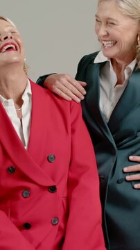 Vertical video: Placing hand, teal blazer woman leaning and laughing for portrait, red blazer