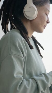 Vertical video: Camera rising, person sketching on tablet using stylus by window in light-green top