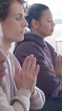 Vertical video: Sitting trio breathing at session start at studio window, prayer hands in hoodies