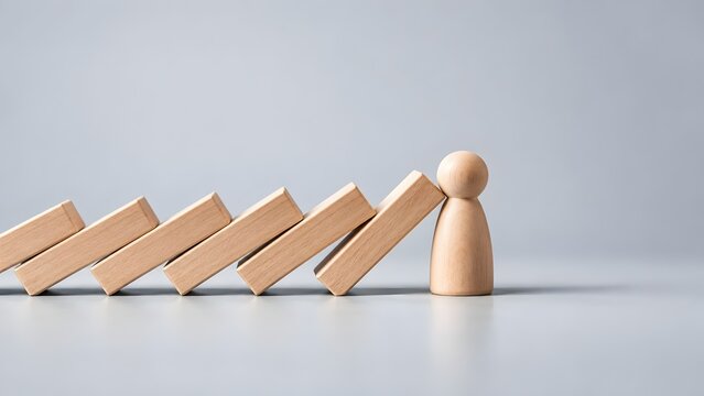 Wooden figure stopping falling dominoes representing resilience protection and preventing a crisis or chain reaction in business or life