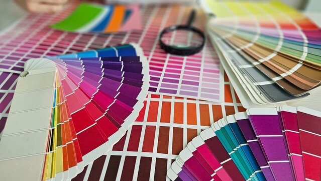 Color swatches and palettes arranged on a table with a magnifying glass for selecting colors concept