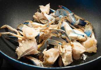 Granchio blu tagliato a pezzi in padella durante la preparazione di una ricetta di mare © MyBionicEye
