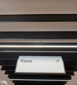 Modernes, minimalistisches Hinweisschild zur Kasse unter einer Lammellendecke, Berlin, Deutschland