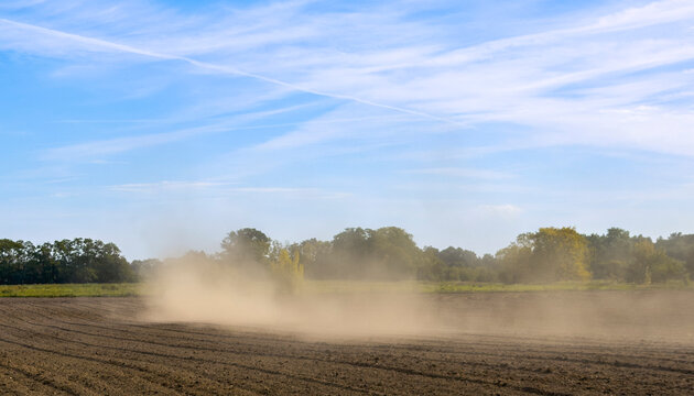 Roter Traktor bei der Aussaat auf einem staubigen Acker in weiter Landschaft unter bew&ouml;lktem Himmel, Berlin, Deutschland