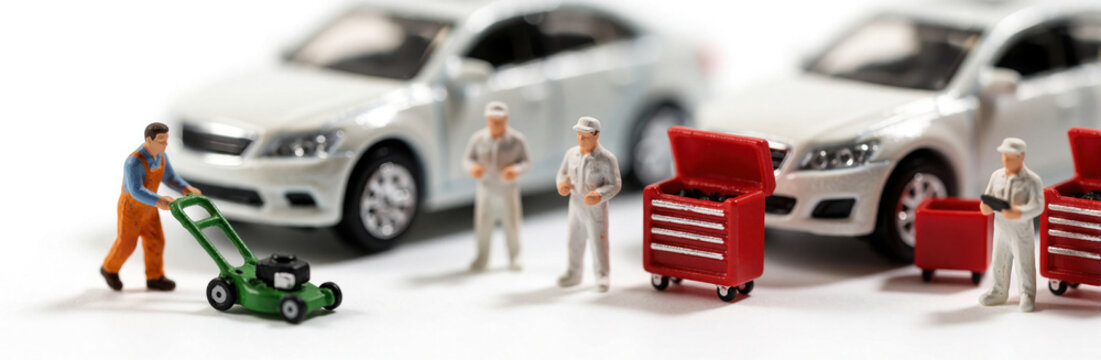 Miniature mechanic workers perform auto repair service in garage. Tiny men work on white cars near red tool chest. Small technician figures fix vehicles, manage car maintenance using pro tools for