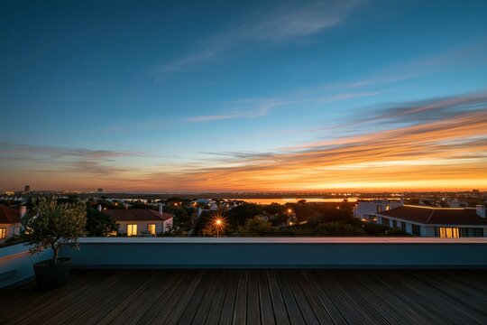 Concrete parapet wall on a modern rooftop terrace with timber decking, featuring a small potted olive tree under a glowing twilight sky for copy space