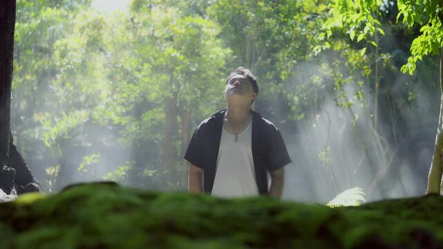 A young man's hand touches the water in a river or a green forest, enjoying his journey, experiencing nature.
