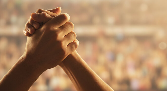 Close-up of two hands clasped in a strong handshake symbolizing unity teamwork and partnership against a blurred crowd background