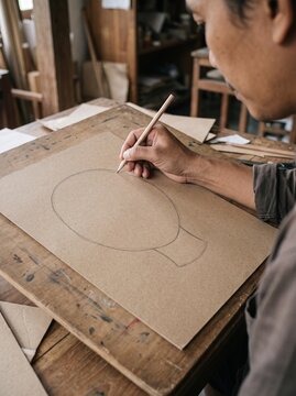 Artisan Sketching a Paper Puppet Character by Hand