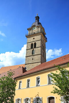Blick auf die katholische Stadtpfarrkirche St. Johannes der T&auml;ufer in Auerbach in der Oberpfalz mit ihrem markanten barocken Kirchturm unter strahlend blauem Sommerhimmel.