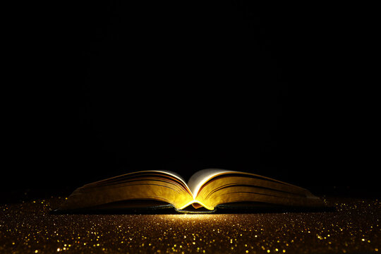 Open book on golden background and dramatic light