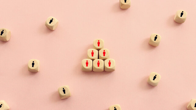Wooden cubes with people icons over pink background, human resources and management concept