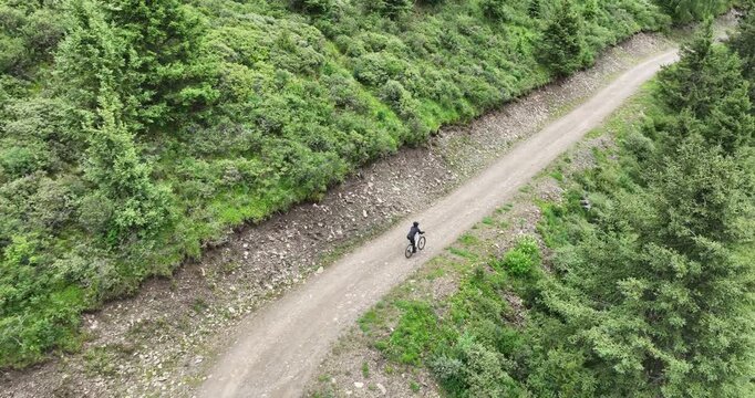 Aerial footage of woman riding mountain bike on beautiful forest mountain trail