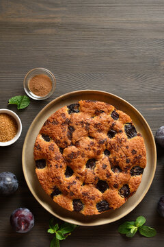 Plum pie on plate on wooden table