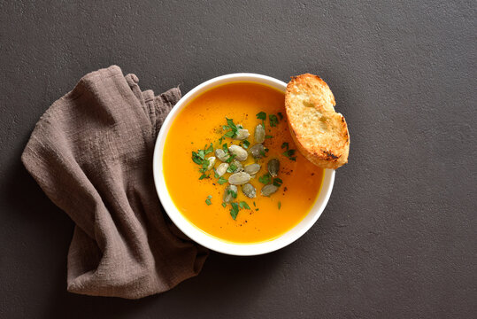 Delicious creamy pumpkin soup garnished with seeds and parsley