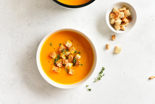 Delicious creamy pumpkin soup garnished with croutons and thyme