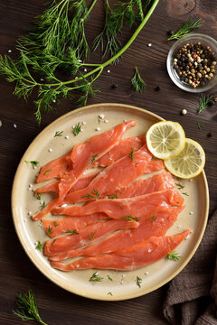Slices of salted salmon on plate on dark wooden table