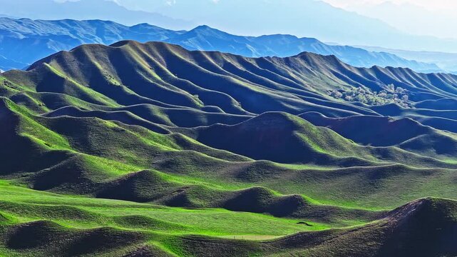 Aerial view of rolling green hills and mountain ridges in Xinjiang, China.