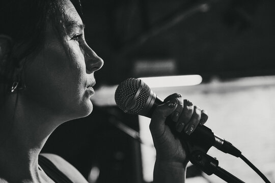 Adult woman singing into microphone during band sound check onstage