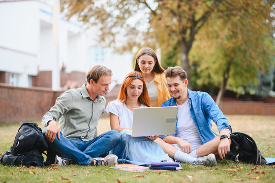 University students collaborating on laptop outdoors at campus