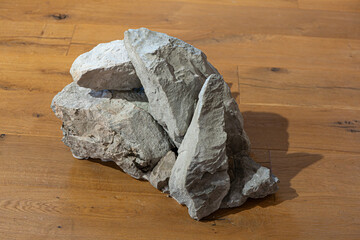 Pile of rough natural stones placed on modern wooden parquet floor, contemporary art installation and interior design concept. © saad