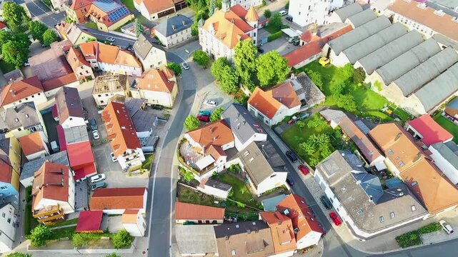 Malerische Luftaufnahme von Auerbach in der Oberpfalz mit der markanten Stadtpfarrkirche, traditionellen roten D&auml;chern und idyllisch gr&uuml;ner Landschaft im Hintergrund unter blauem Himmel.