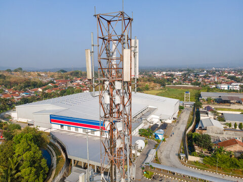 Aerial View of a Telecommunication Tower with Radio Masts and Equipment Near a Retail Warehouse in the Morning in Purwokerto, Central Java, Indonesia.