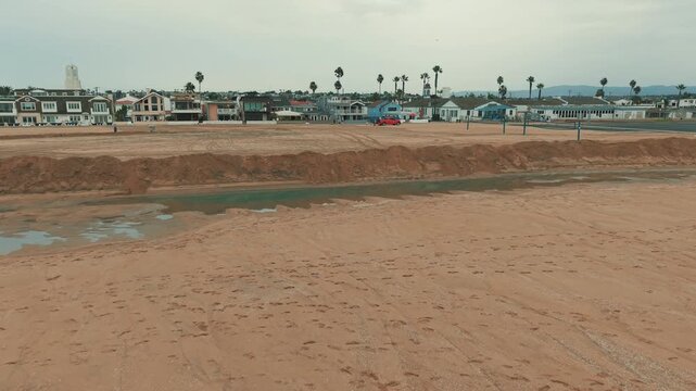 Side view of massive protective sand berms built along Newport Beach shoreline to defend nearby coastal homes against high tides and flooding.
