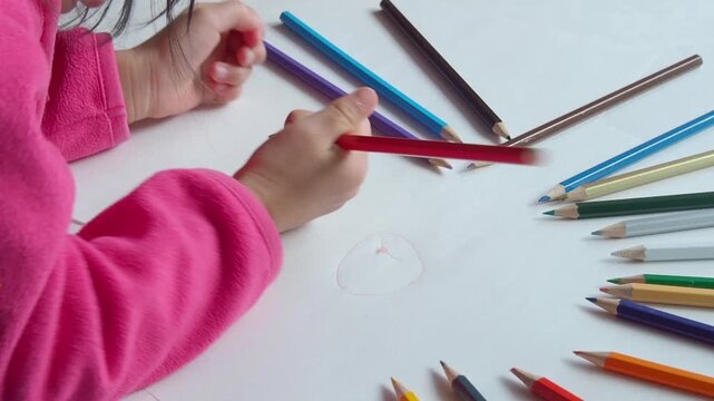 家のリビングでカラフルな色鉛筆で絵を描いている幼児の子供の姿