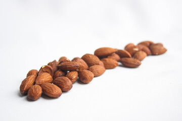 Fototapeta premium Row of roasted almond nuts arranged on a white background