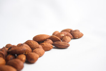 Fototapeta premium Row of roasted almond nuts arranged on a white background