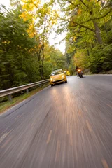 Motorcyclist Overtaking a Small Yellow Car on a Forest Road © Lukas Gojda