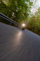 Fototapeta premium Motorcyclist Riding a Forest Road at Dusk