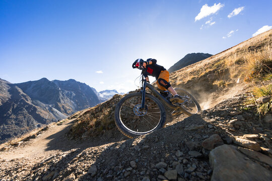 Mountain Biker Descending a Rocky Alpine Trail Above a Glacier
