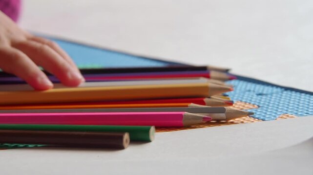 家のリビングでカラフルな色鉛筆で絵を描いている幼児の子供の姿