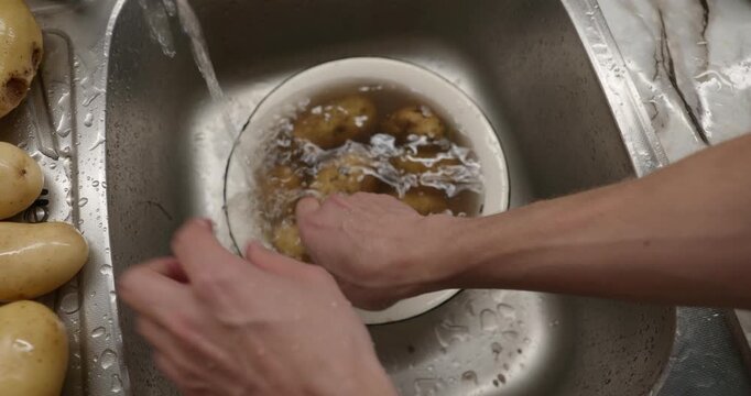 Close-up male hands wash rinse potatoes. 4K 10-bit
