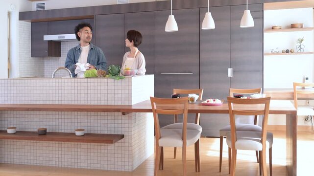 おしゃれで綺麗な新築住宅やマンションのモダンなキッチンで家事を協力して行う日本人夫婦、 お皿を拭く家事分担と共働き家庭の快適な暮らしの動画