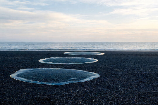 Translucent water rings resting above a black pebble shore