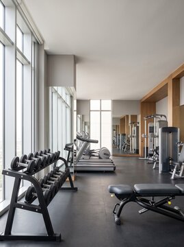 Modern fitness club interior with dumbbells, workout bench and strength training equipment in a bright, spacious gym.