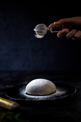 The head chef poses in the kitchen, set against a dark floor, with white dough and flour creating a striking contrast. © myCan