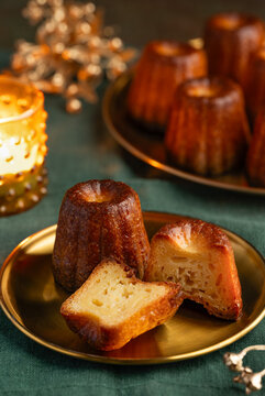 Two canel&eacute;s on a gold plate. A traditional French dessert with rum and vanilla and a caramelized  crispy crust. Selective focus.