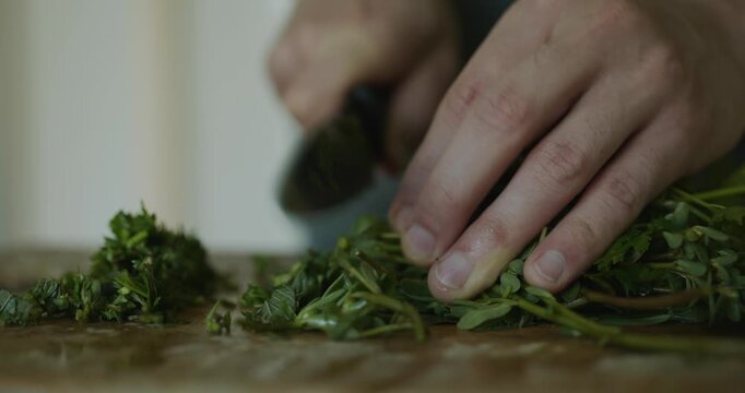 Close-up male hands chop cut green leaves herbs for salad. 4K 10-bit