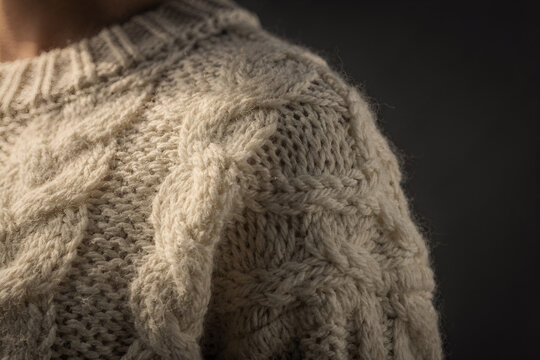 Chunky cream cable knit wool texture close up on dark background
