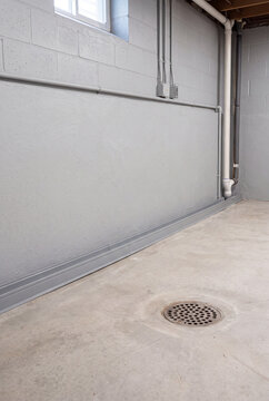 Empty basement with gray walls and floor drain