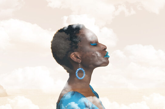 Contemplative Young Black Woman Looking Upward Against Clouds And Sky Background, Exuding Calmness And Serenity. Posed In Ethereal Setting That Suggests Dreams And Imagination. Concept: Dreamy.